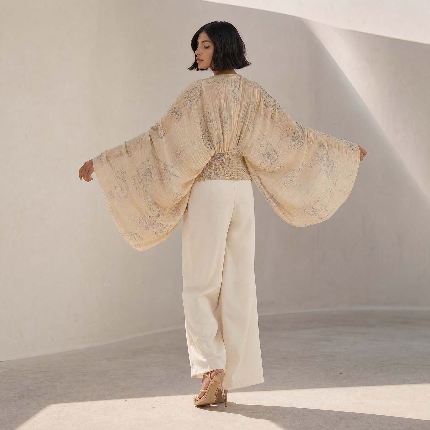 Linnea Cape Blouse — back view, arms extended showing cape drape