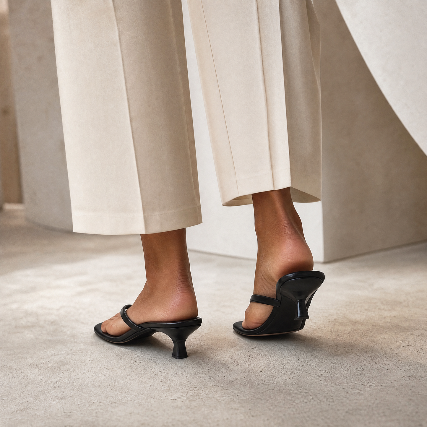 Sigrid Thong Sandal in Black — 3/4 rear view showing sculptural heel